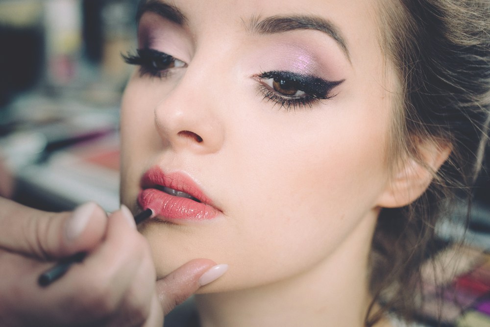 Visagistin trägt Lippenfarbe auf